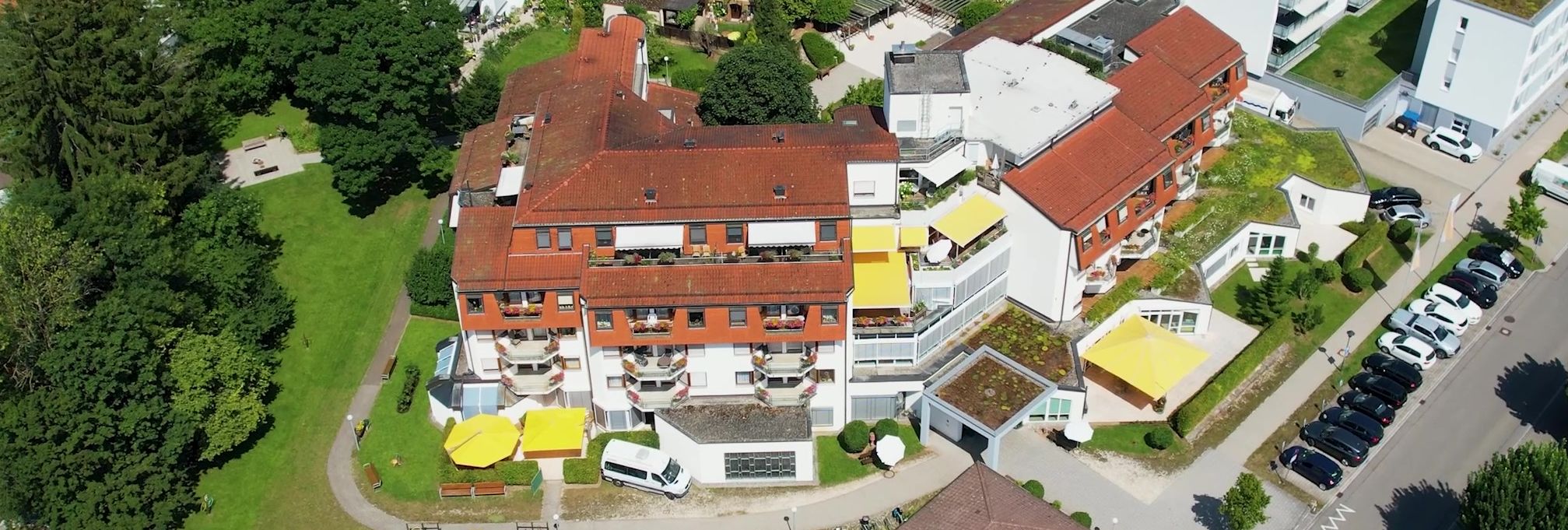 Luftaufnahme eines Wohnviertels mit mehrstöckigen Wohnhäusern, Gärten und Parkplätzen